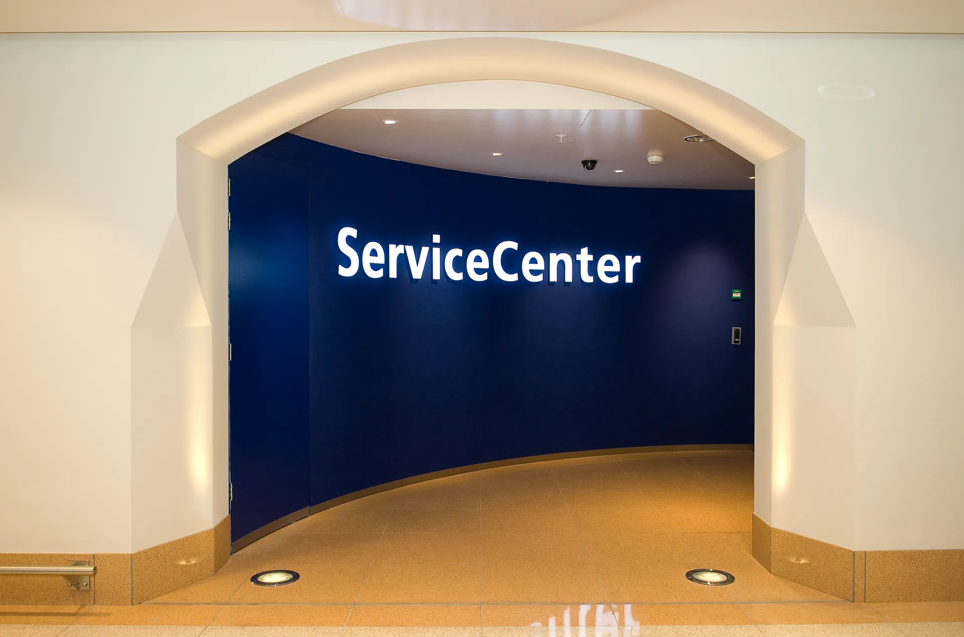 Een entree van een servicecentrum met een blauwe muur en witte boog, voorzien van een bord met de tekst Service Center.