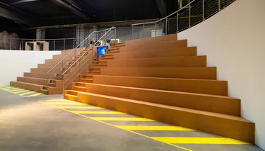 Een moderne industriële trap met een metalen leuning en betonnen treden, met een strak en functioneel ontwerp.