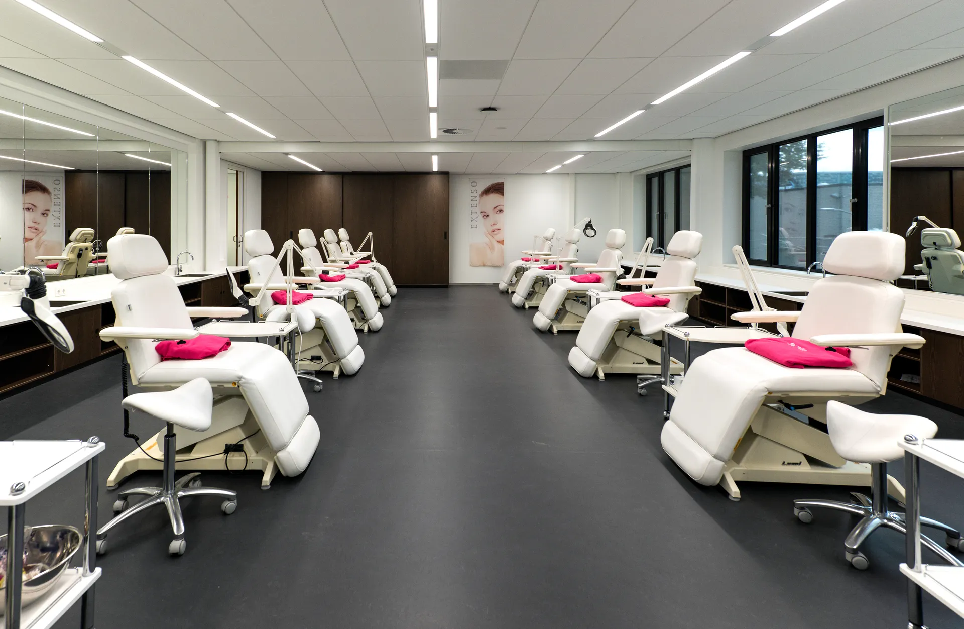 Een moderne tandartspraktijk met witte en roze stoelen, een grote spiegel en een schone, klinische sfeer.