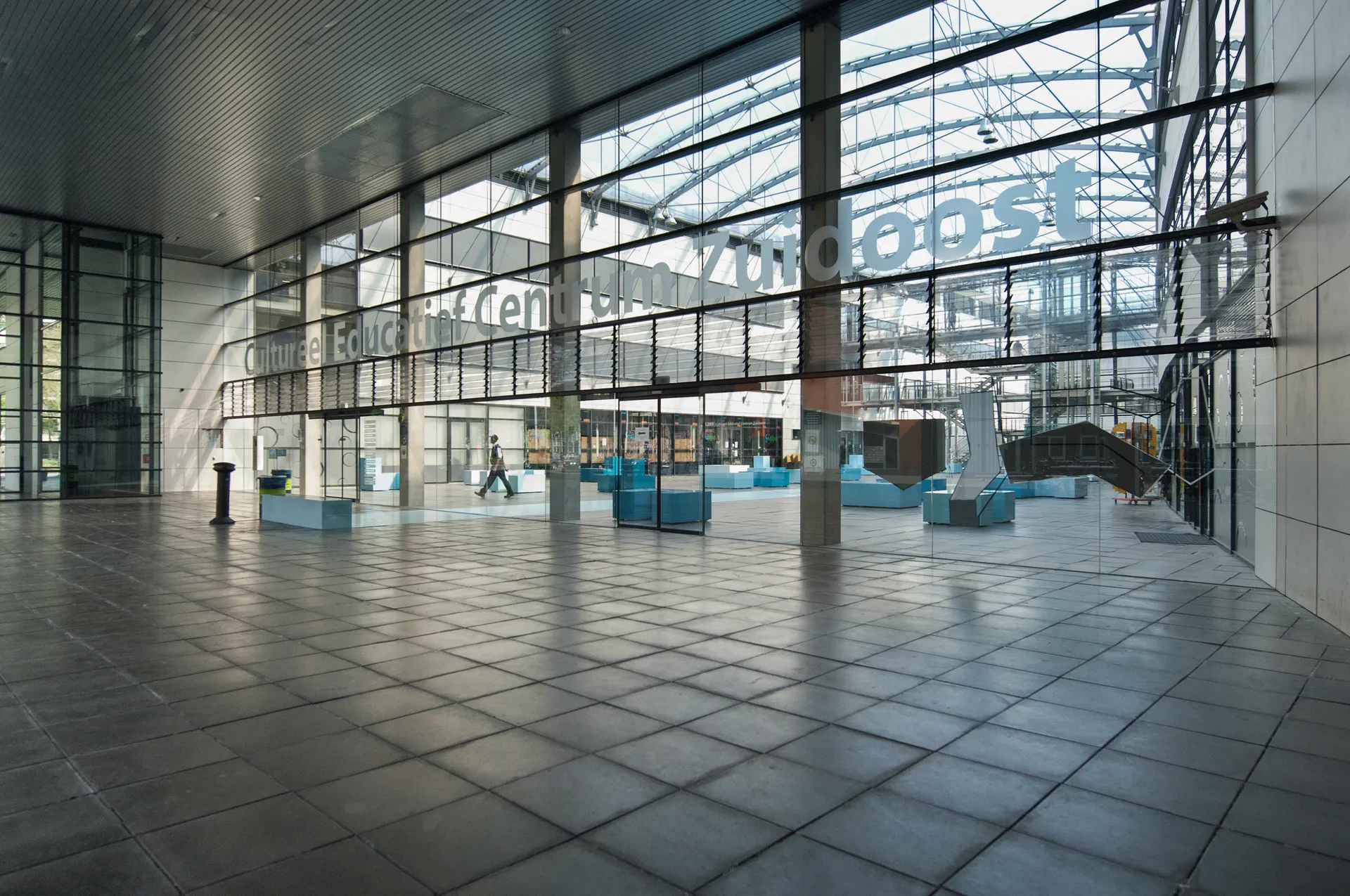 Een groot, open glazen atrium met een hoog plafond en natuurlijk licht, perfect voor een modern kantoor of commerciële ruimte.