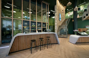 Een moderne receptieruimte in een kantoor met een strakke, ronde balie en een glazen wand met uitzicht naar buiten.