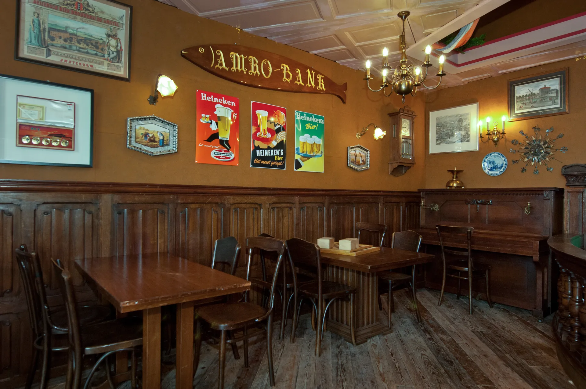 Gezellig bruin café interieur met donkerhouten meubels, decoratie aan de muur en een centrale typische bar.