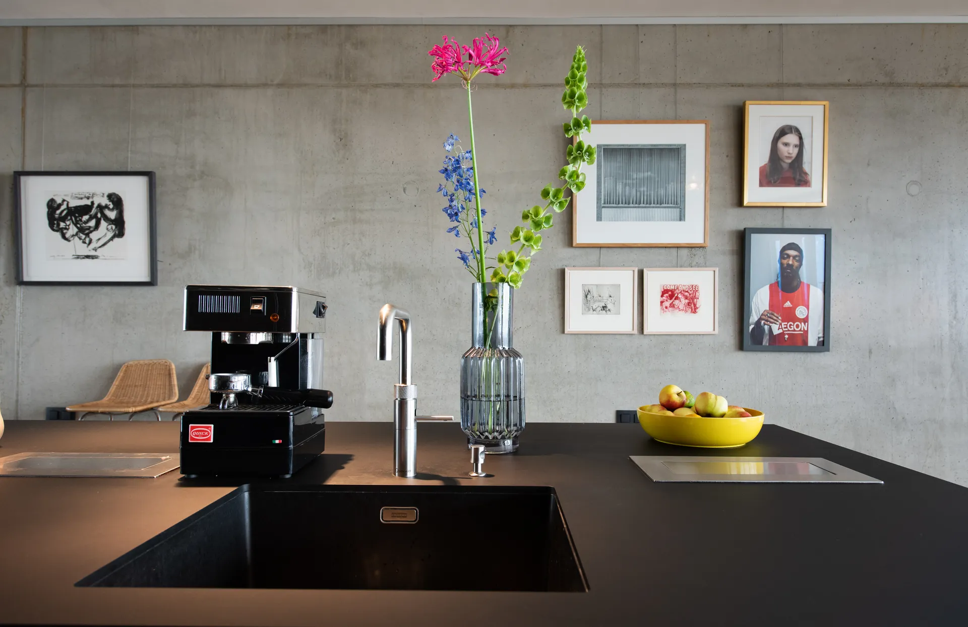 Een moderne keuken met een industrieel randje met een donker blad met spoelbak en koffiemachine en strakke decoratie.